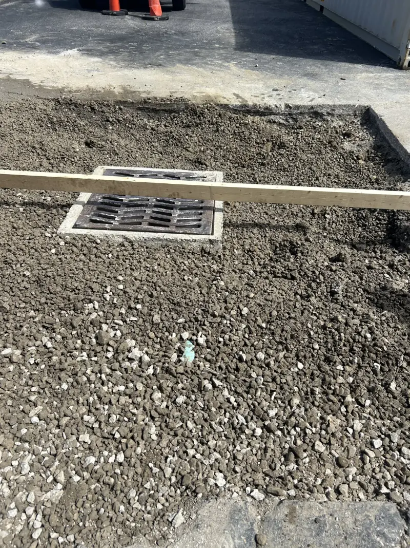 Drainage grate set within a compacted aggregate work area