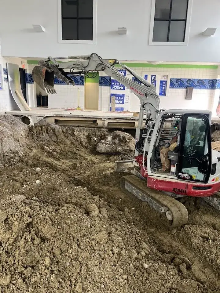 Compact excavator working inside a commercial interior